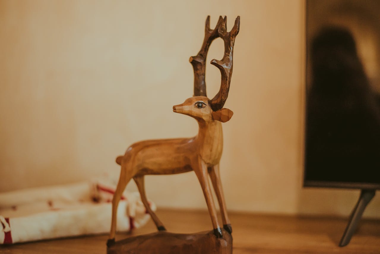 services-02 A detailed wooden deer sculpture on a table, showcasing fine craftsmanship in a cozy indoor setting.