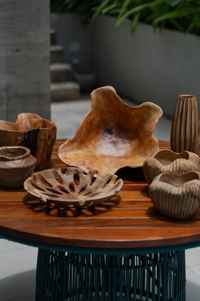 who-we-are A collection of carved wooden decorative bowls and vases on an outdoor table.
