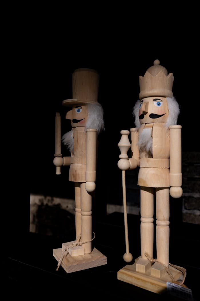 services-03 Two wooden nutcracker figures in a dark, dramatic lighting setting.