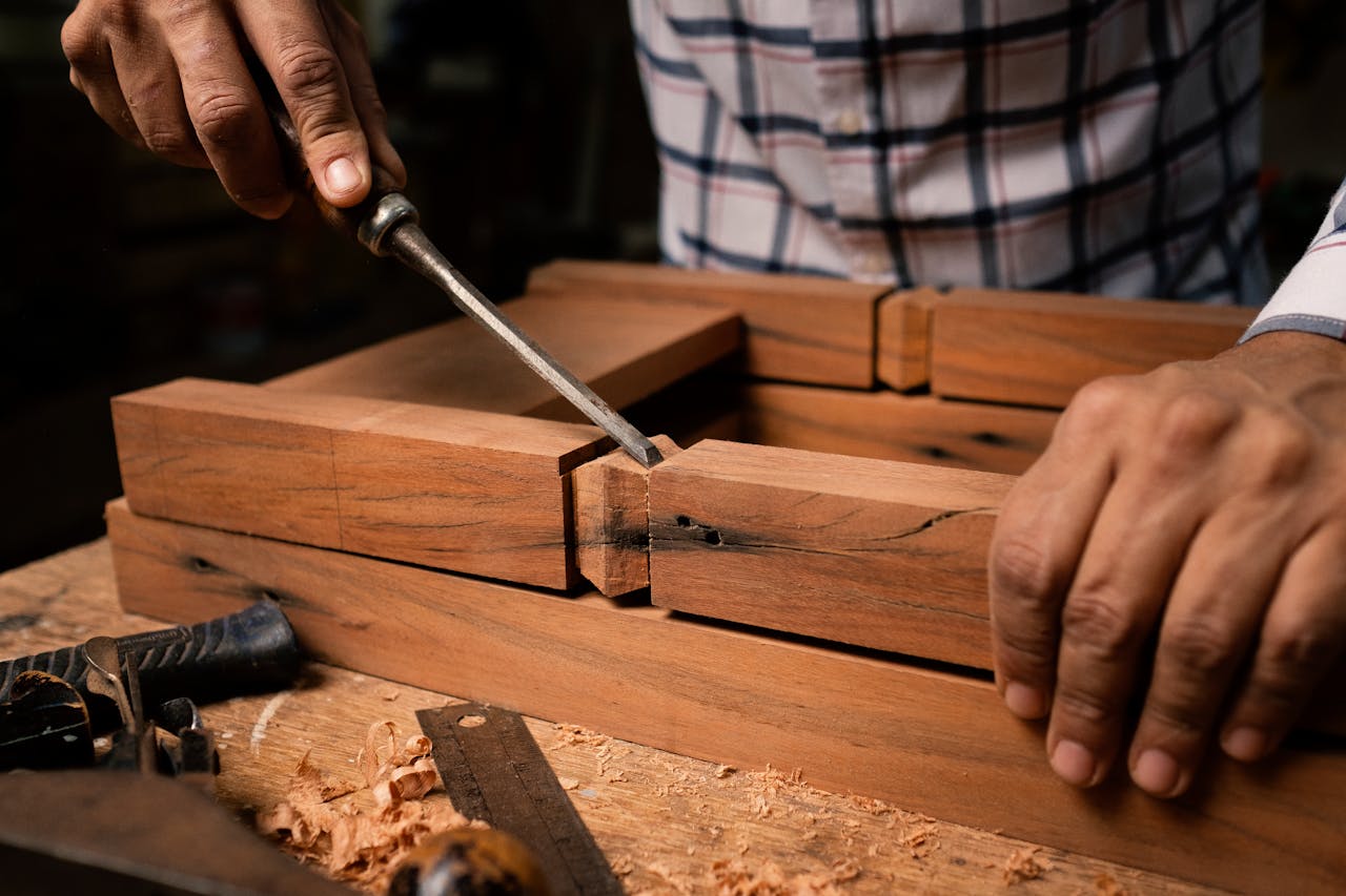 Focused view of a person skillfully using a chisel on wooden pieces indoors.